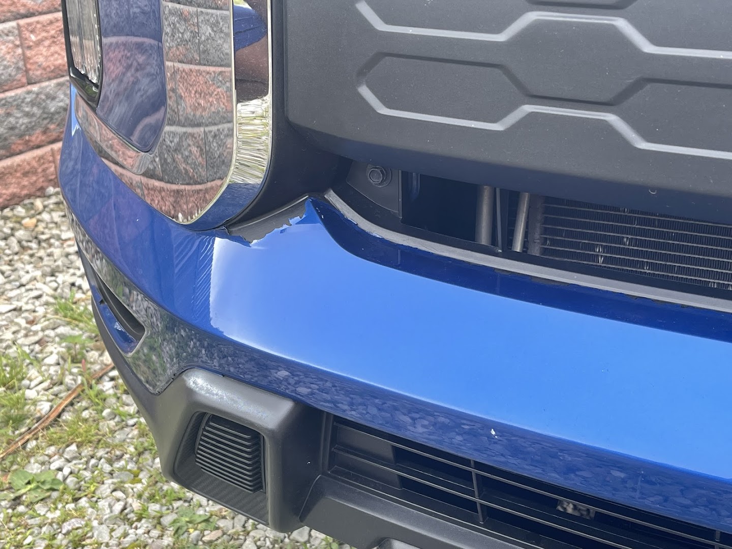 Dented front bumper on a blue SUV showing collision damage before repair